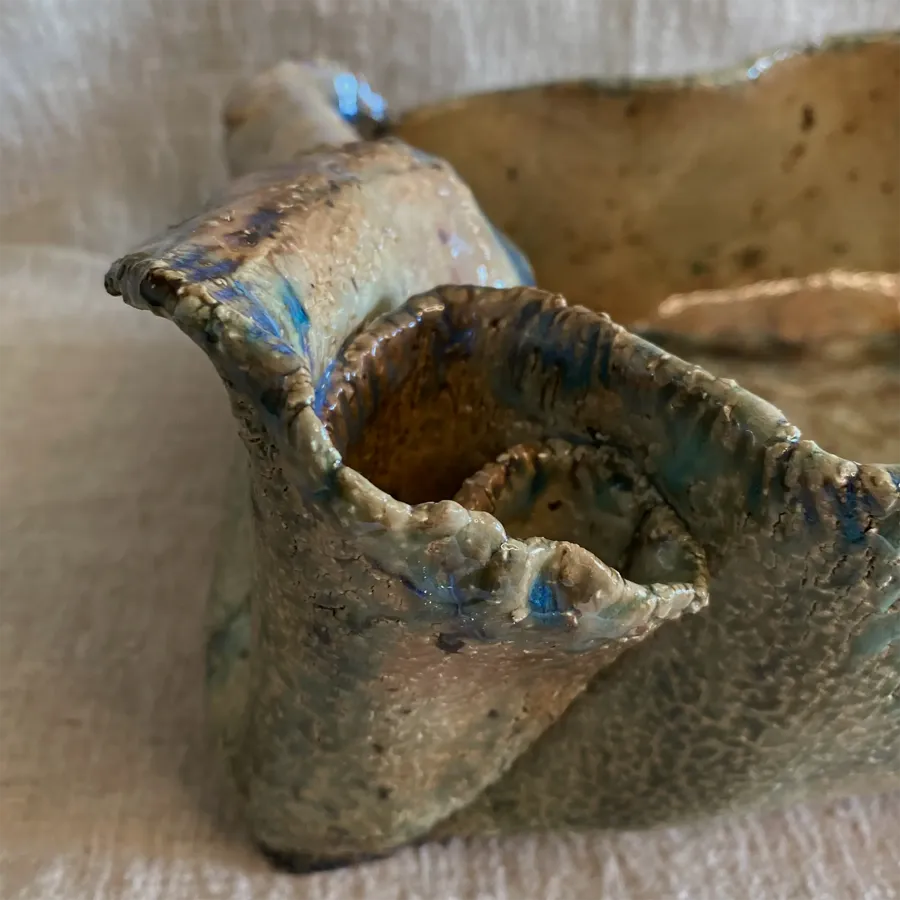 Detalle de una pieza cerámica de borde orgánico sobre una tela de lino.