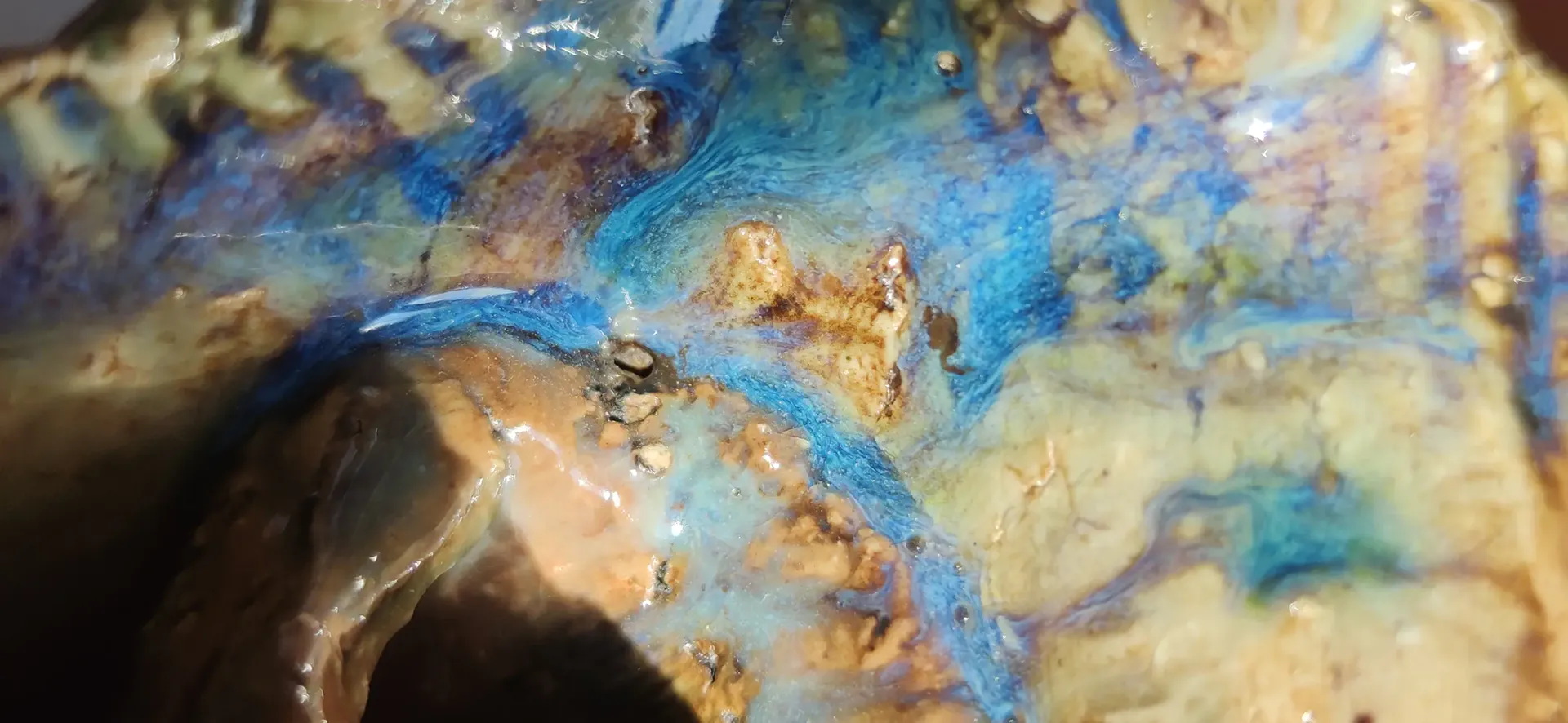Detalle de una superficie cerámica con relieves azules y tonos arena.